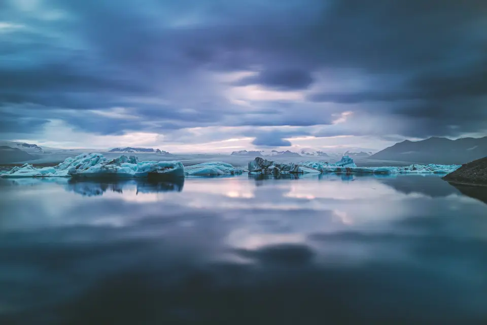 A stranded blue iceberg on a black-sand shore