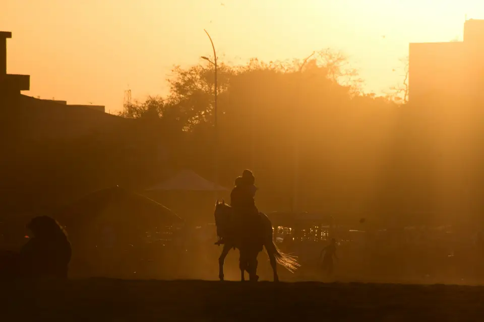 A Patagonian gaucho on horseback backlit at dusk