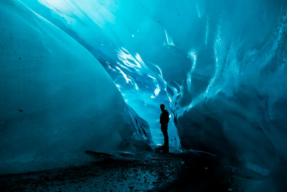 Inside a glacier ice cave glowing electric blue