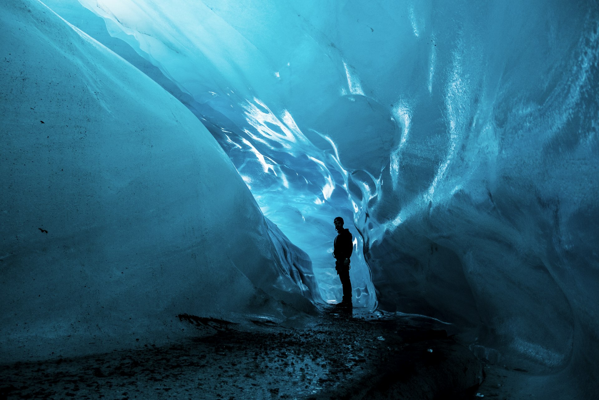 Inside a glacier ice cave glowing electric blue