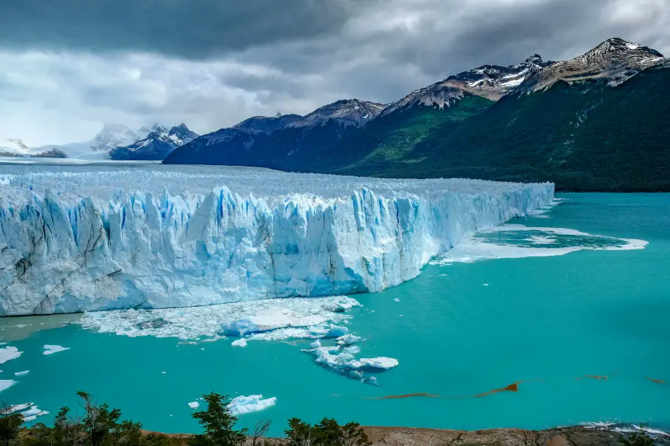 Blue ice calving off Perito Moreno glacier into the lake at dawn
